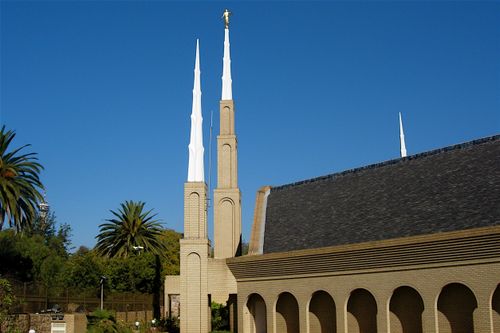 A side front view of the Johannesburg South Africa Temple and spires, with local vegetation seen growing to the side.