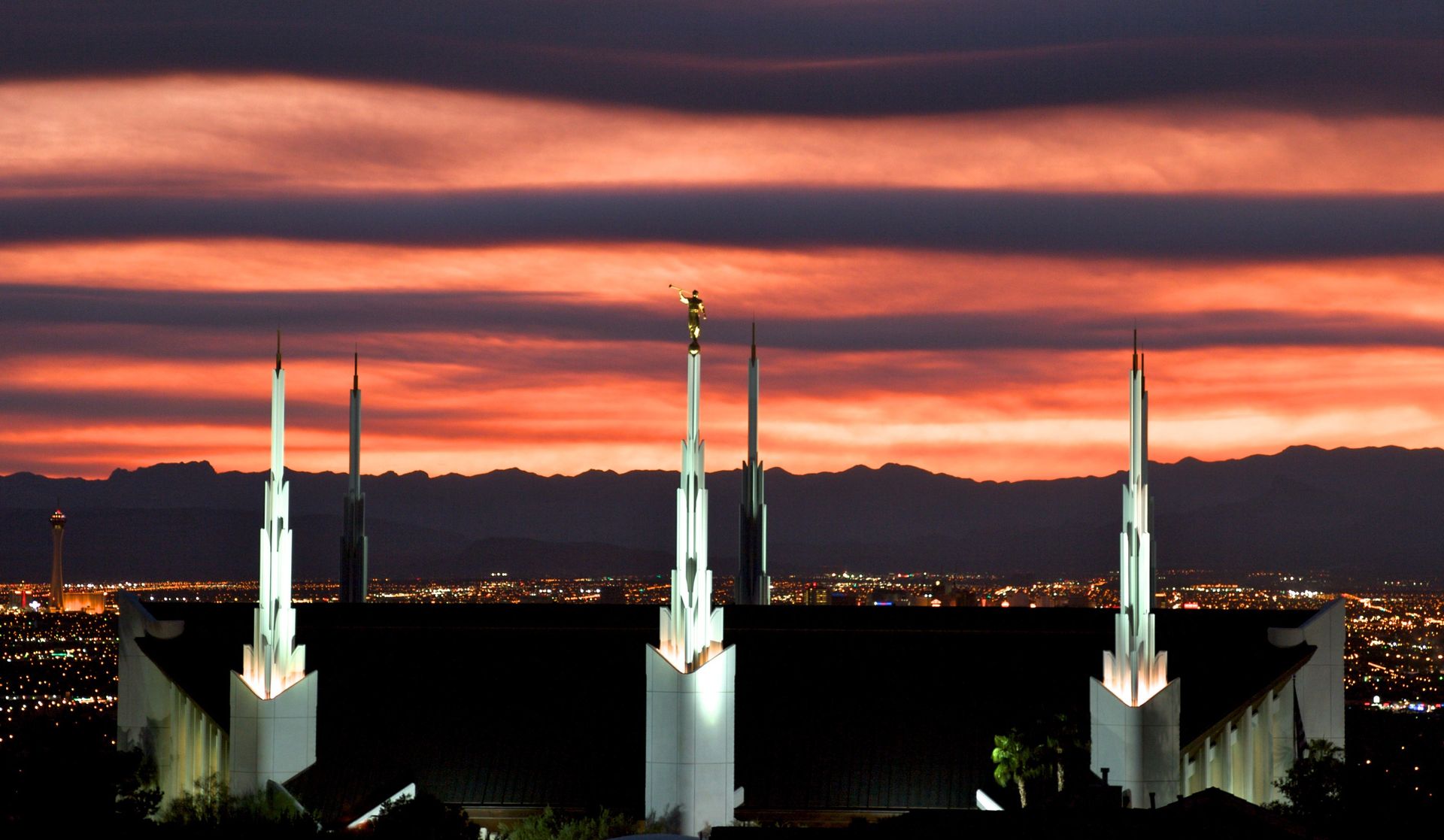The Las Vegas Nevada Temple in the evening, including an illuminated sky and the spires of the temple.  