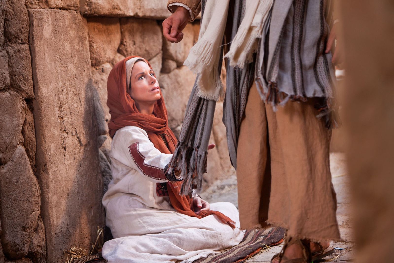 A woman with an issue of blood touches the clothes of Jesus.