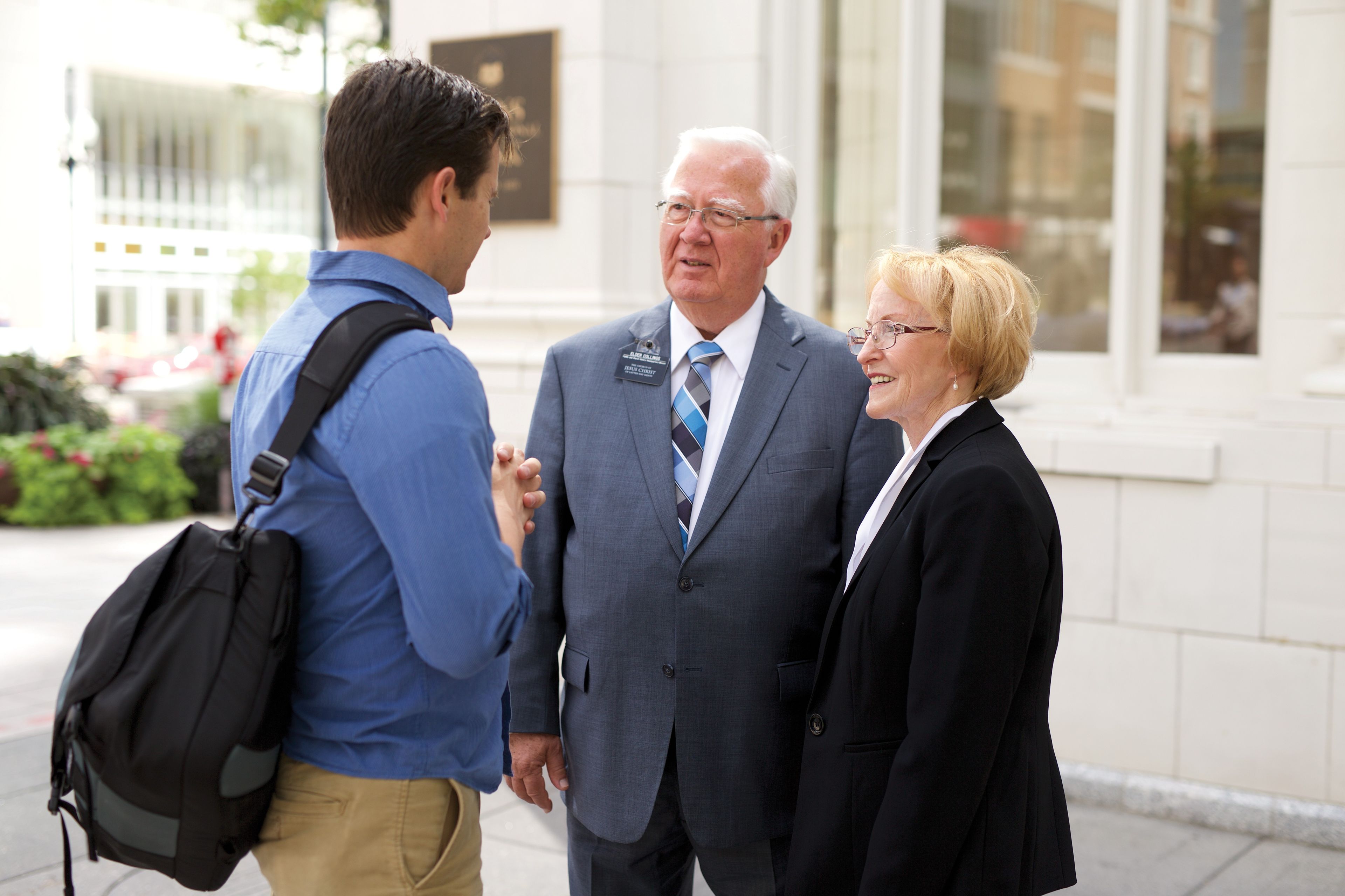 A senior missionary couple standing outside and talking with a man.