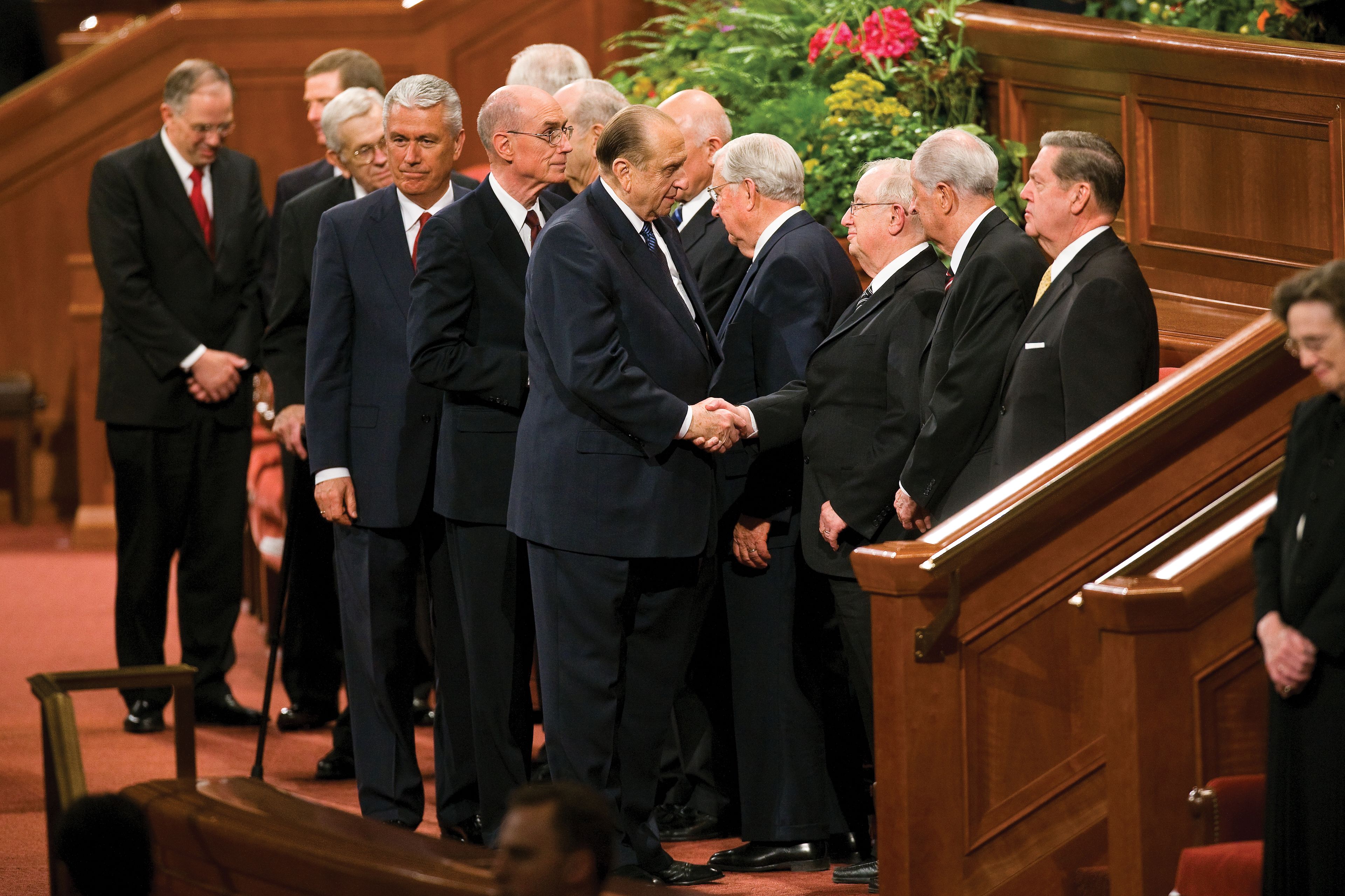 Thomas S. Monson shakes hands with members of the Quorum of the Twelve Apostles on the stand at the Conference Center.