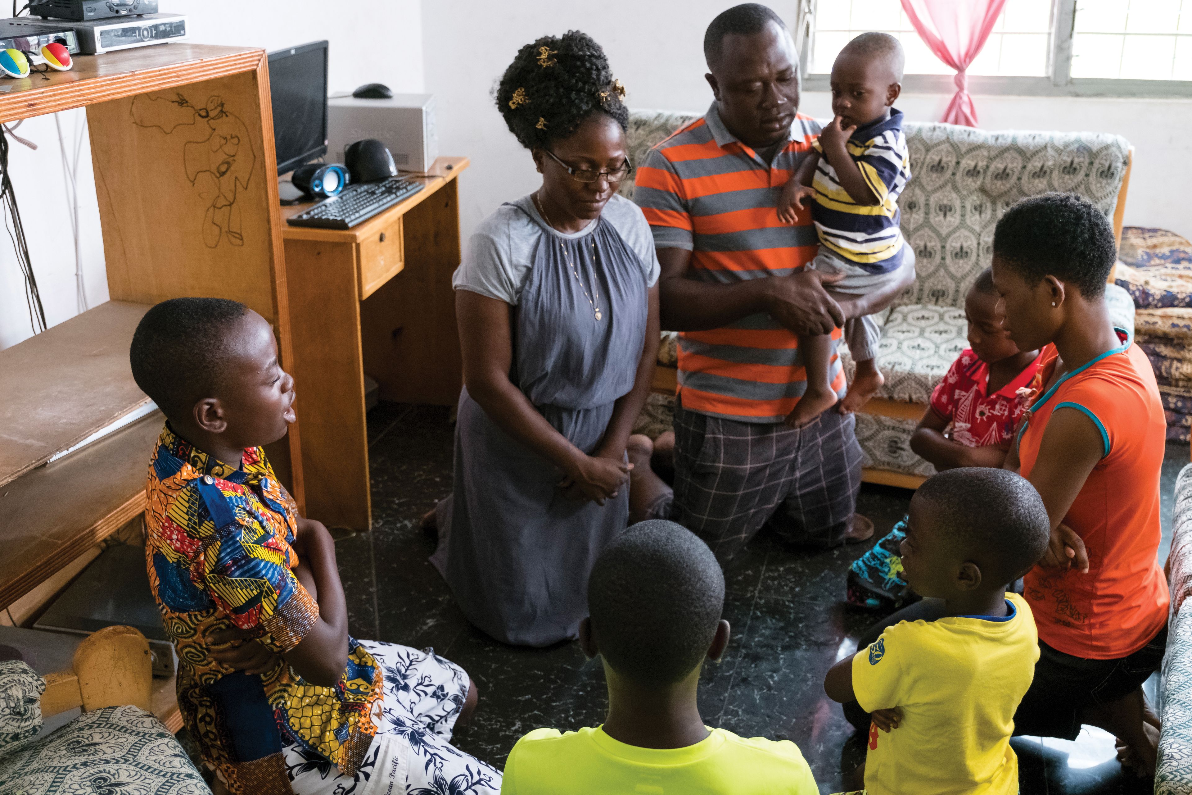 A family in Ghana kneeling and praying together.