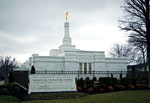 The Nashville Tennessee Temple and grounds surrounded by a black fence, outside of which is the temple’s sign.