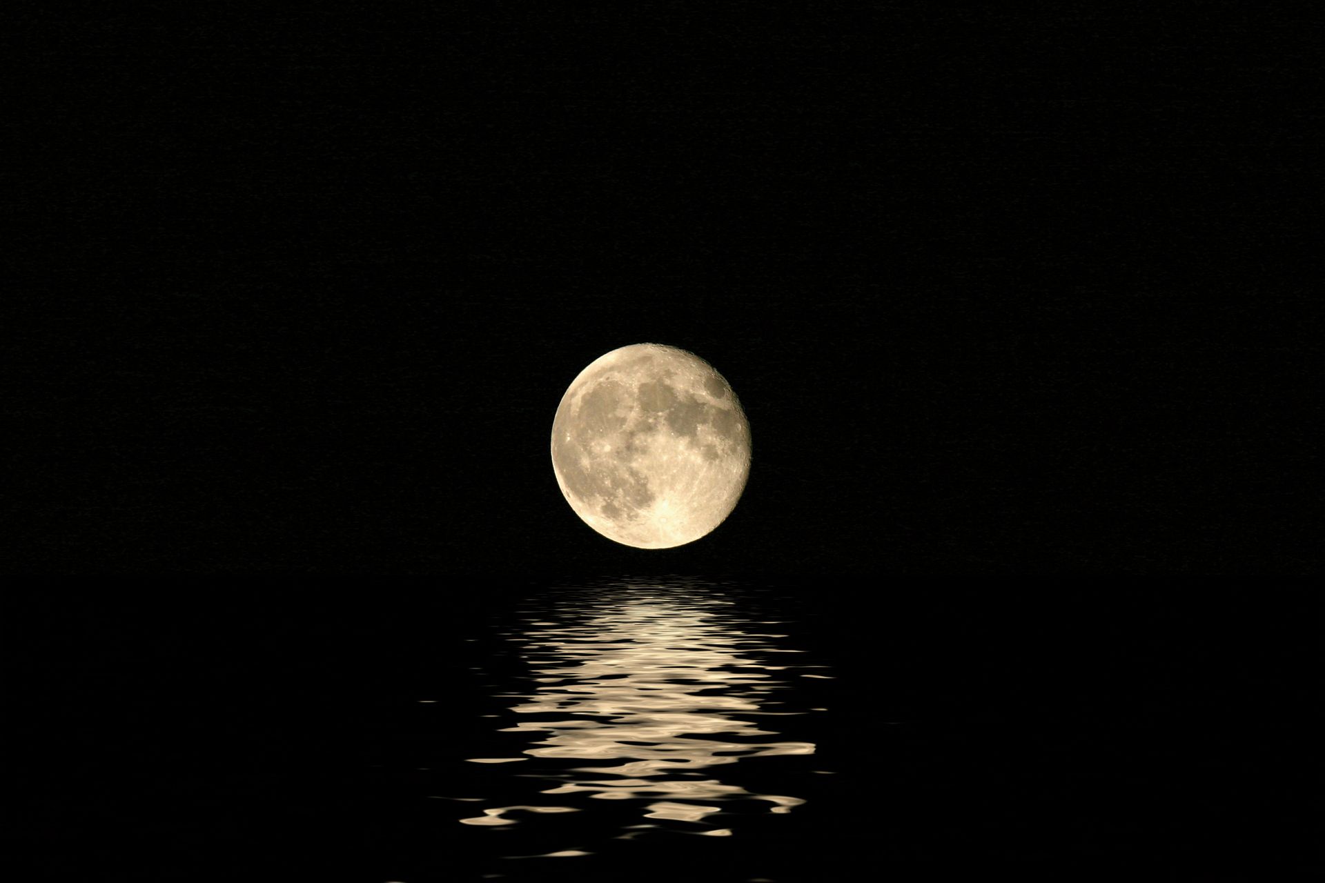 A full moon rises over the water.