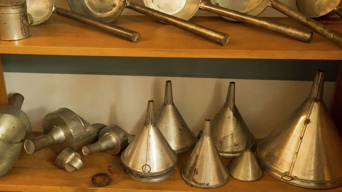 Tin funnels on a wooden shelf.