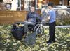 Kid helps man in wheelchair rake leaves
