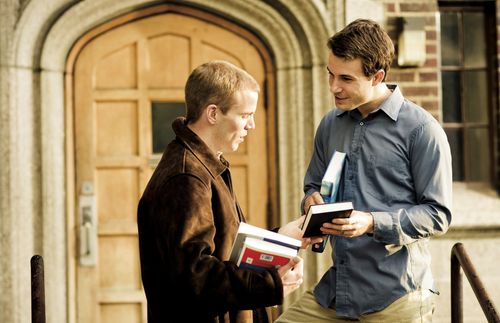 man handing Book of Mormon to other man