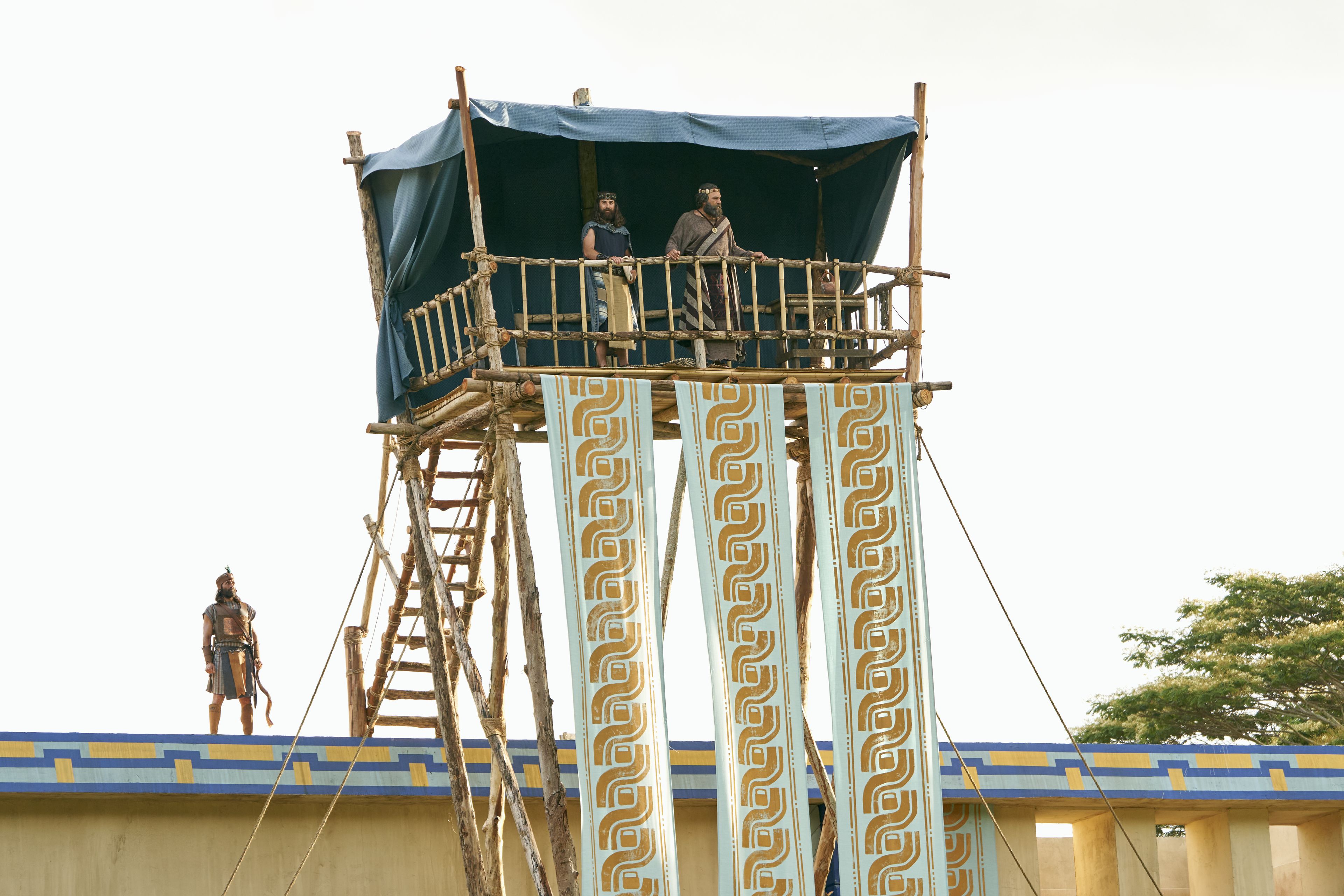 King Benjamin and Mosiah stand together on a tower. King Benjamin speaks to his people in the Land of Zarahemla.