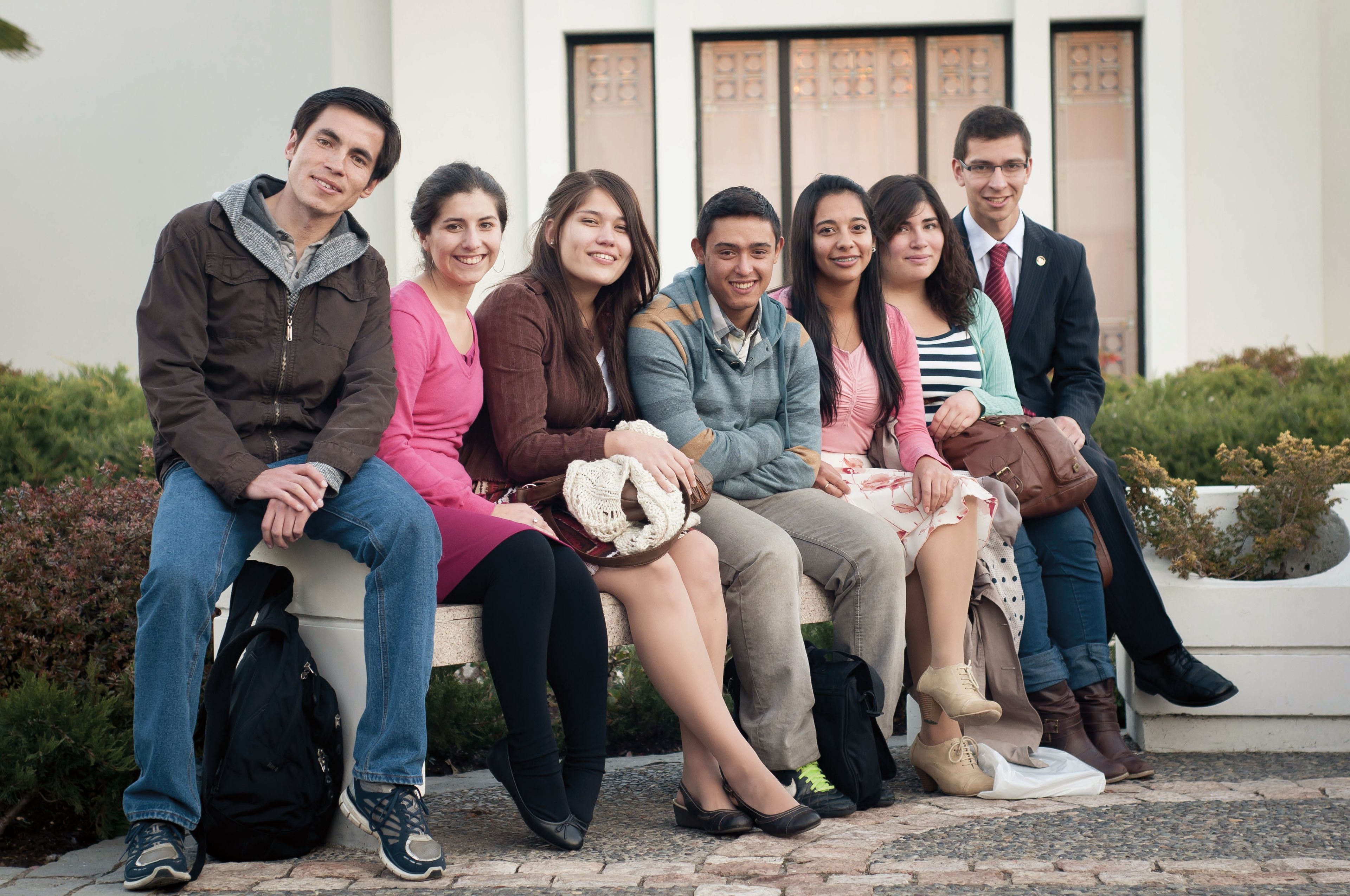 A group of youth sit on a bench outside the Santiago Chile Temple.