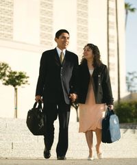 An Hispanic couple with temple bags walking outside the Los Angeles California Temple.