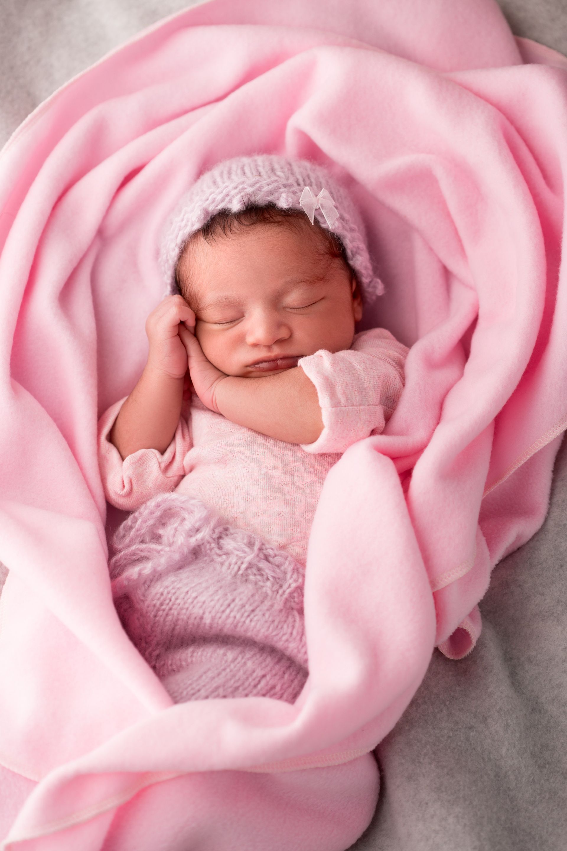 A newborn girl sleeping in a pink blanket.