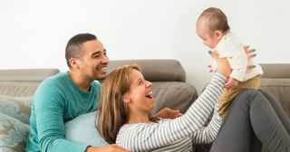 a husband and wife smile at their baby