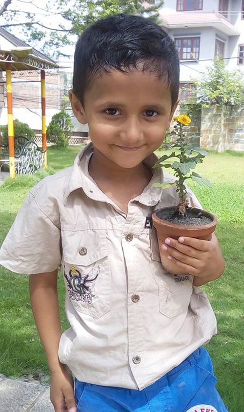 Photo d’un garçon souriant tenant une plante en pot