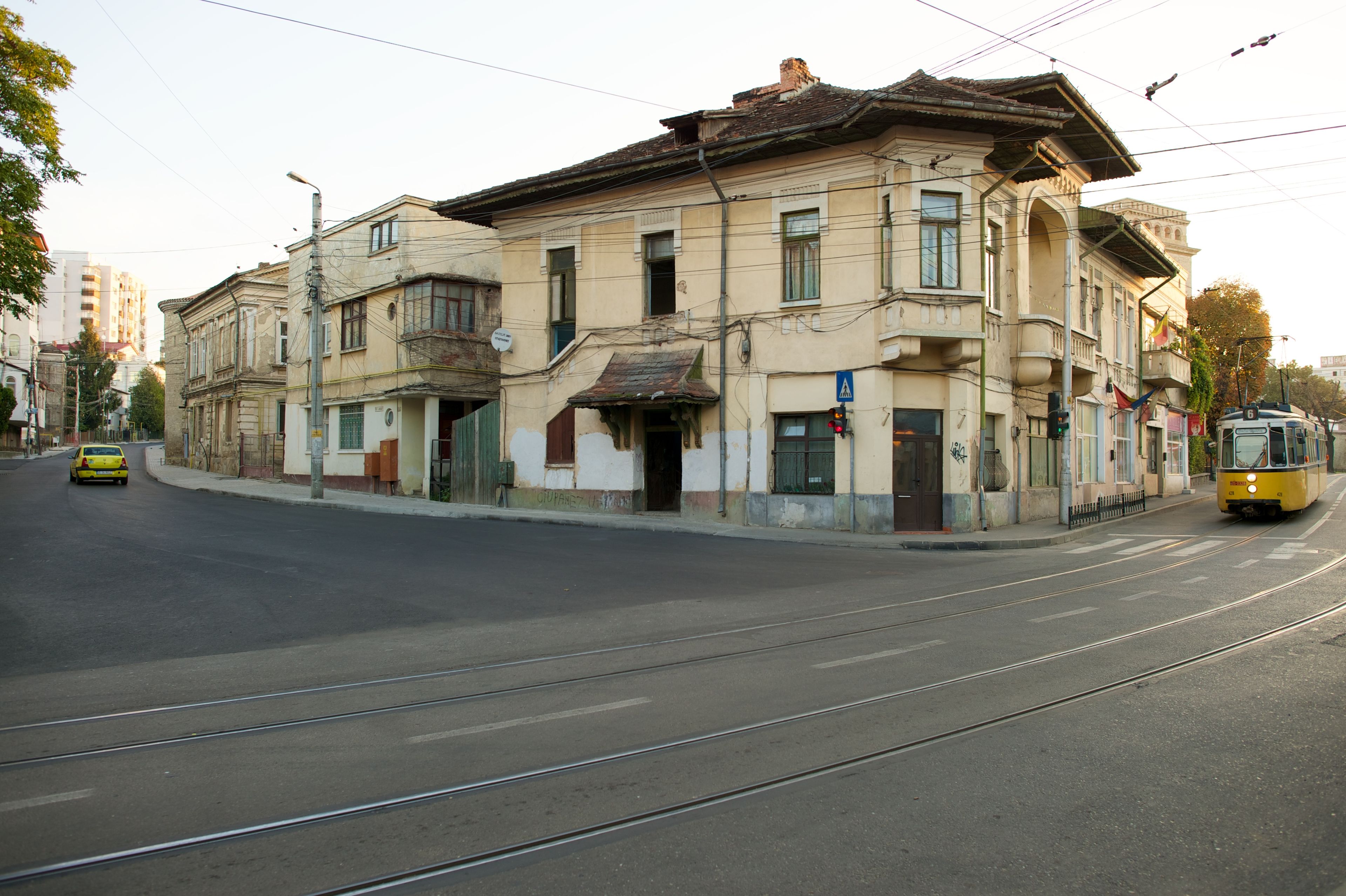A row of buildings and a yellow and white train on a street in Romania.