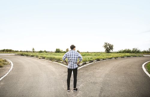 young adult man standing at crossroads