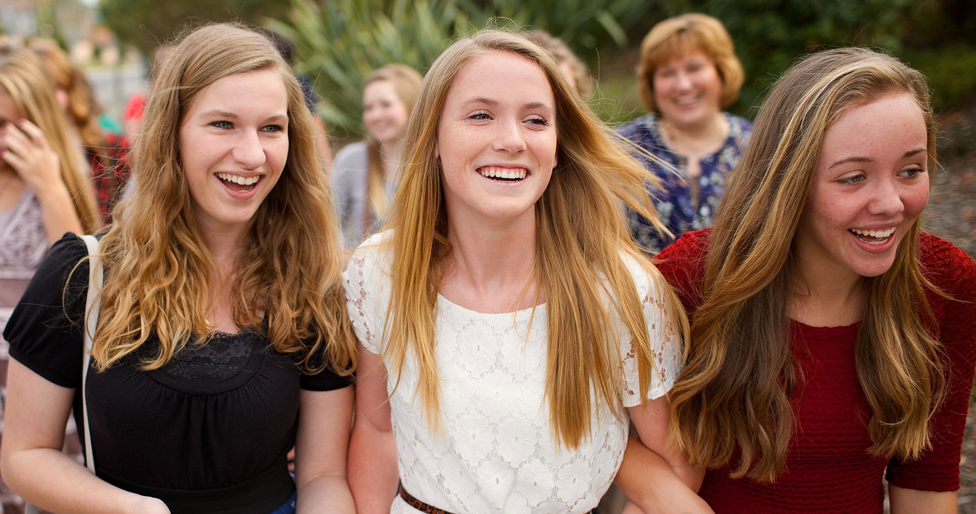 Large group of women (young, old, elderly, youth) walking down a sidewalk.  They are dressed in Sunday clothes as if they are on their way to church.  They look happy and are excited to be on their way.