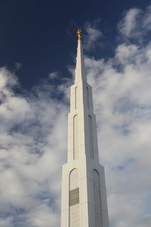 A view of the Manila Philippines Temple spire, with a blue sky and clouds in the distance.