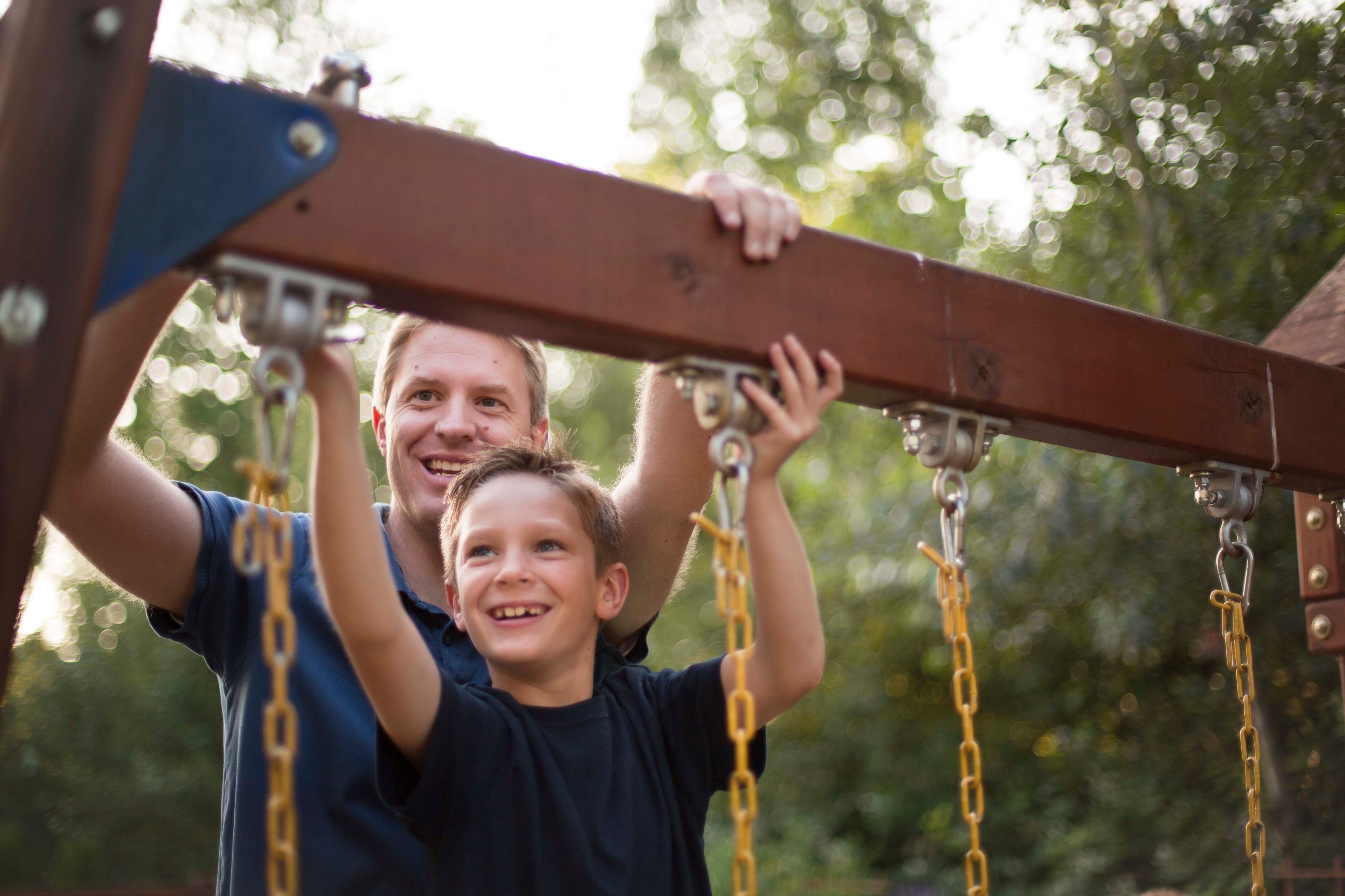 A father and son working on a swing set together. 