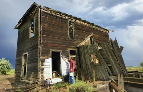 man whitewashing old house