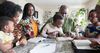 family in Africa around a table reading scriptures together