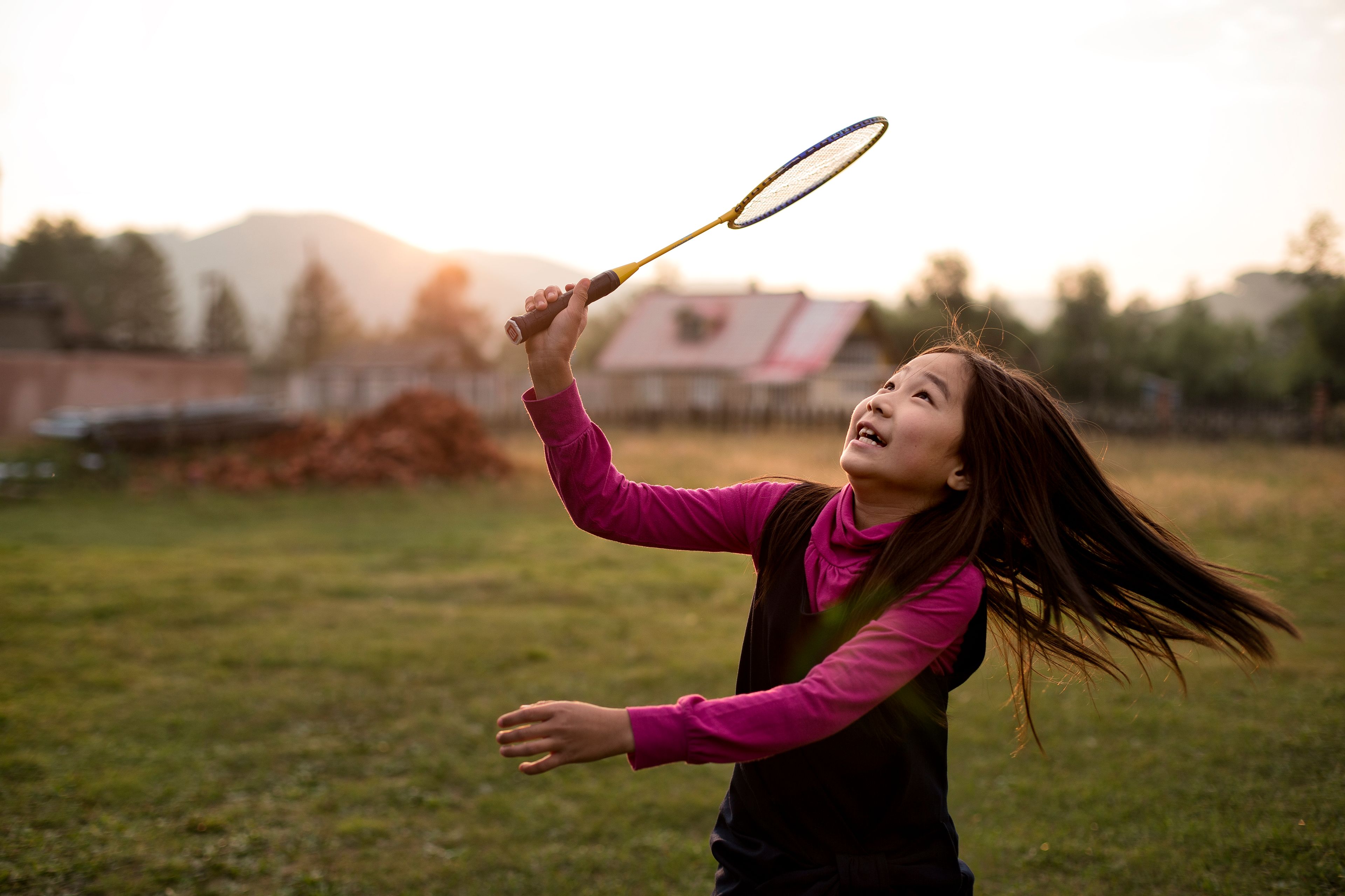A girl plays badminton outside.