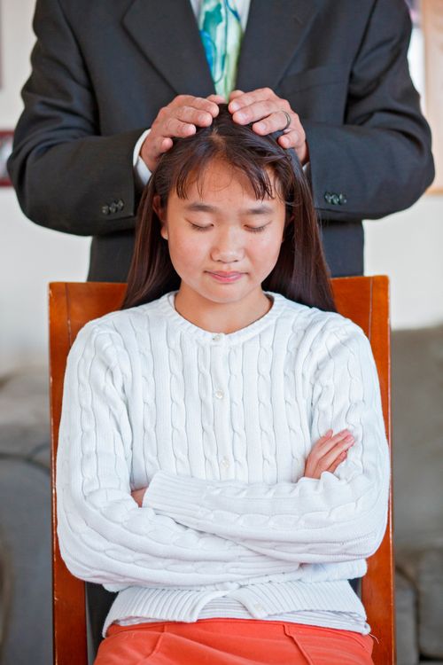 young woman receiving priesthood blessing