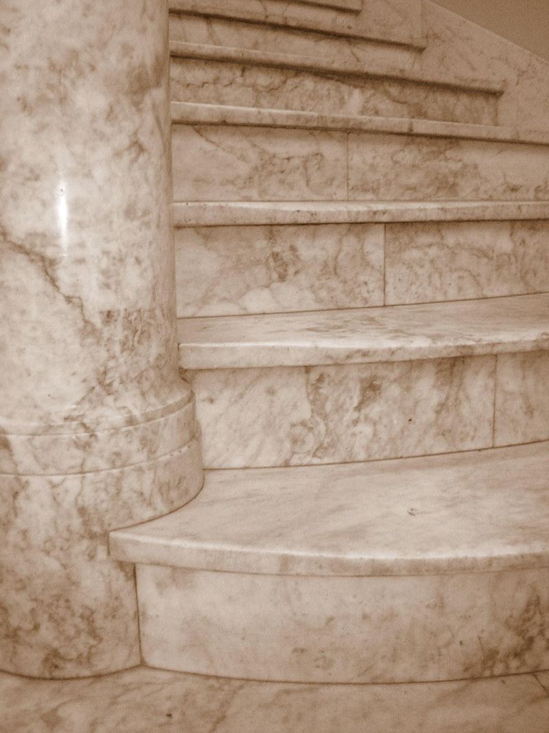 A marble staircase curving slightly around a pillar.