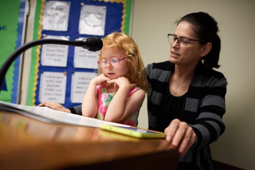 girl speaking at podium in church with woman behind her