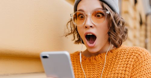 young woman looking shocked at mobile phone