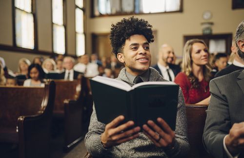 young man holding a hymnbook in church