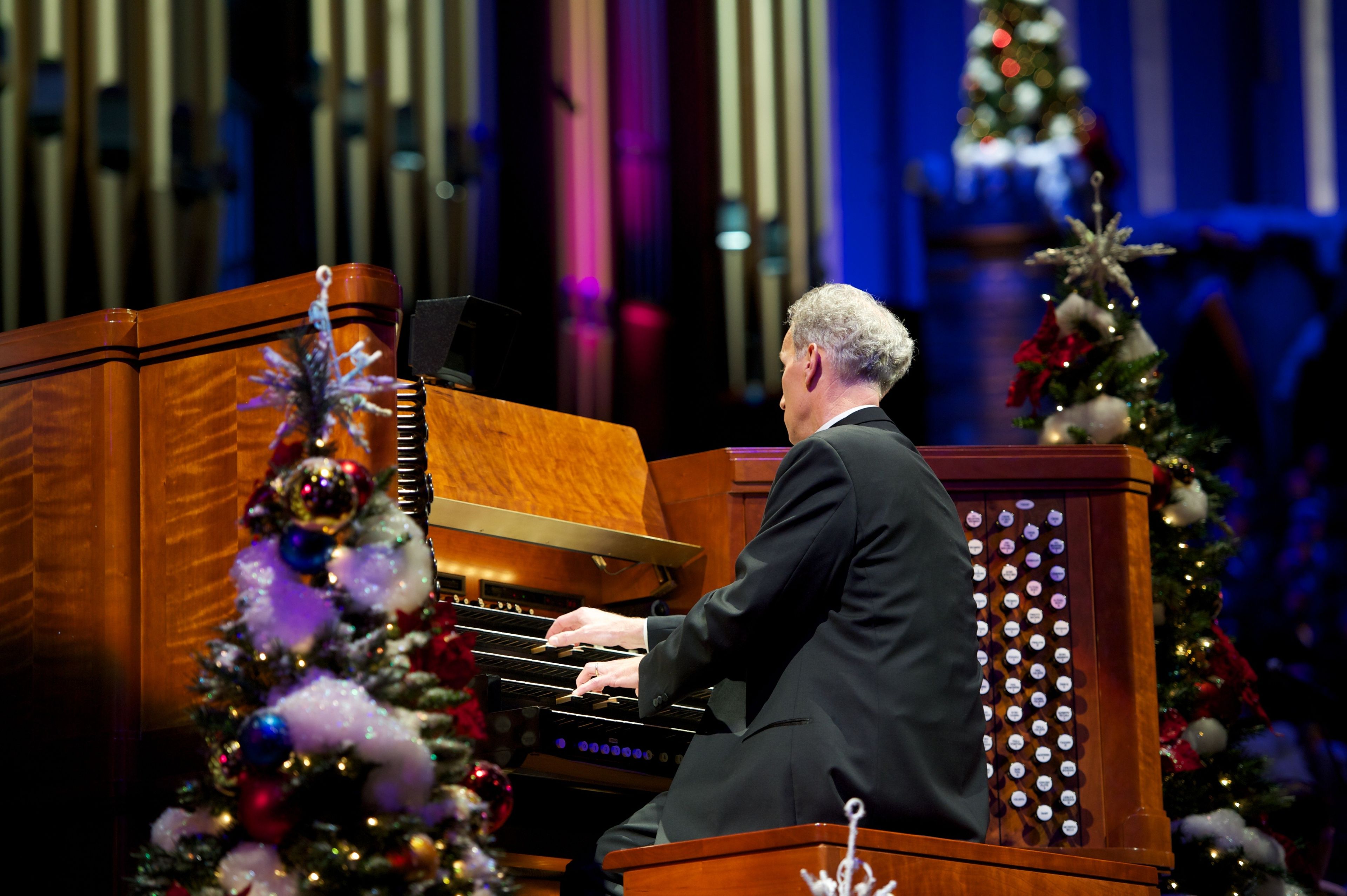 A man in a black suit playing the organ in the 2011 Christmas concert.