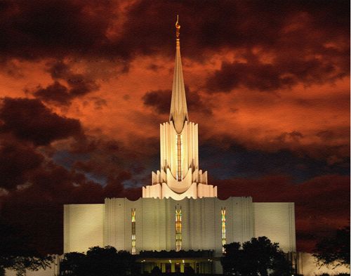 The front of the Jordan River Utah Temple at night, with a deep orange sky in the distance and the temple’s windows illuminated by inside light.