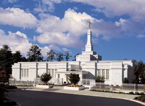 The front of the Columbia South Carolina Temple during the daytime, with a portion of the parking lot in the foreground.