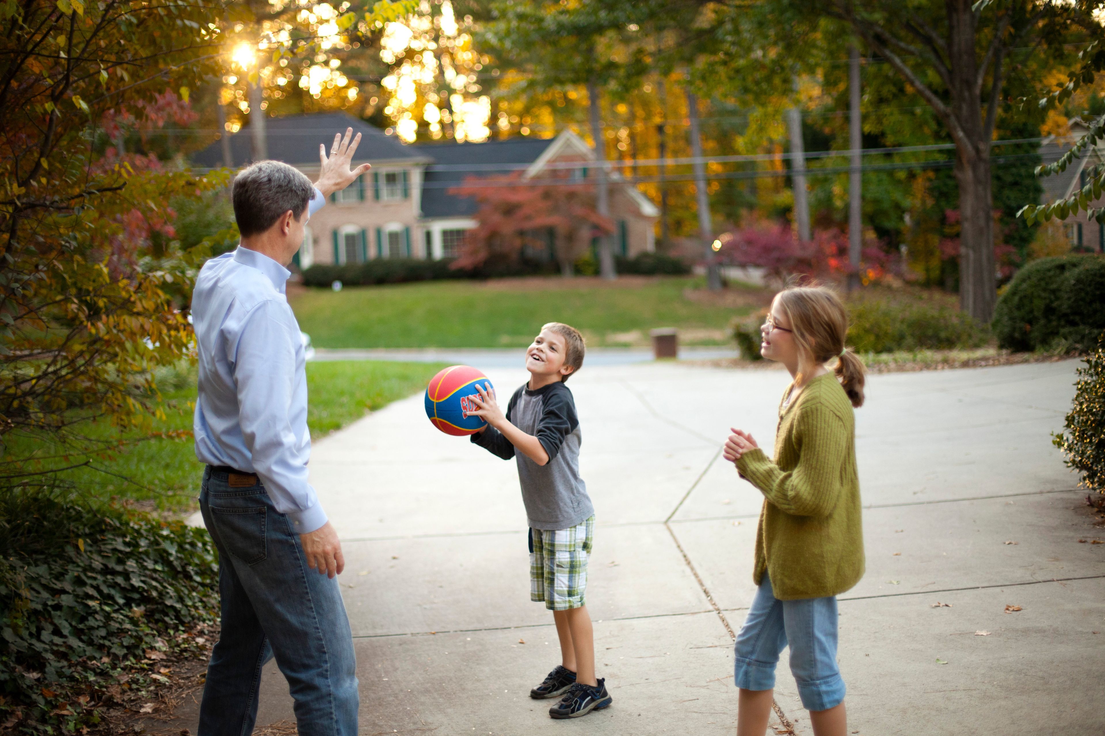 A father plays basketball with his son and daughter.