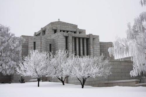 The Cardston Alberta Temple in the winter, with snow on the lawns and the trees that surround the temple.