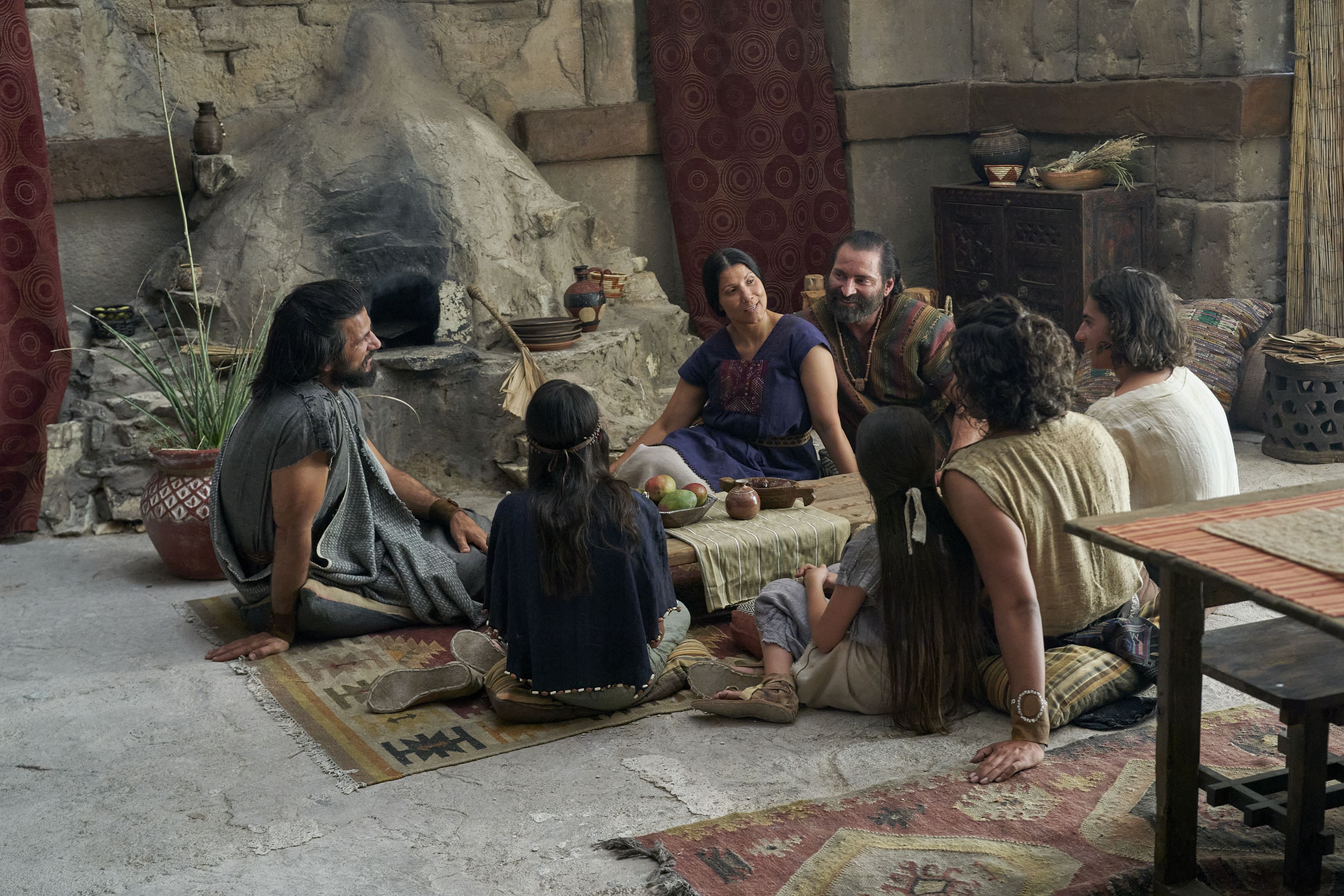 Alma the Younger and Amulek and his family sit and speak together in the house of Amulek in the city of Ammonihah.