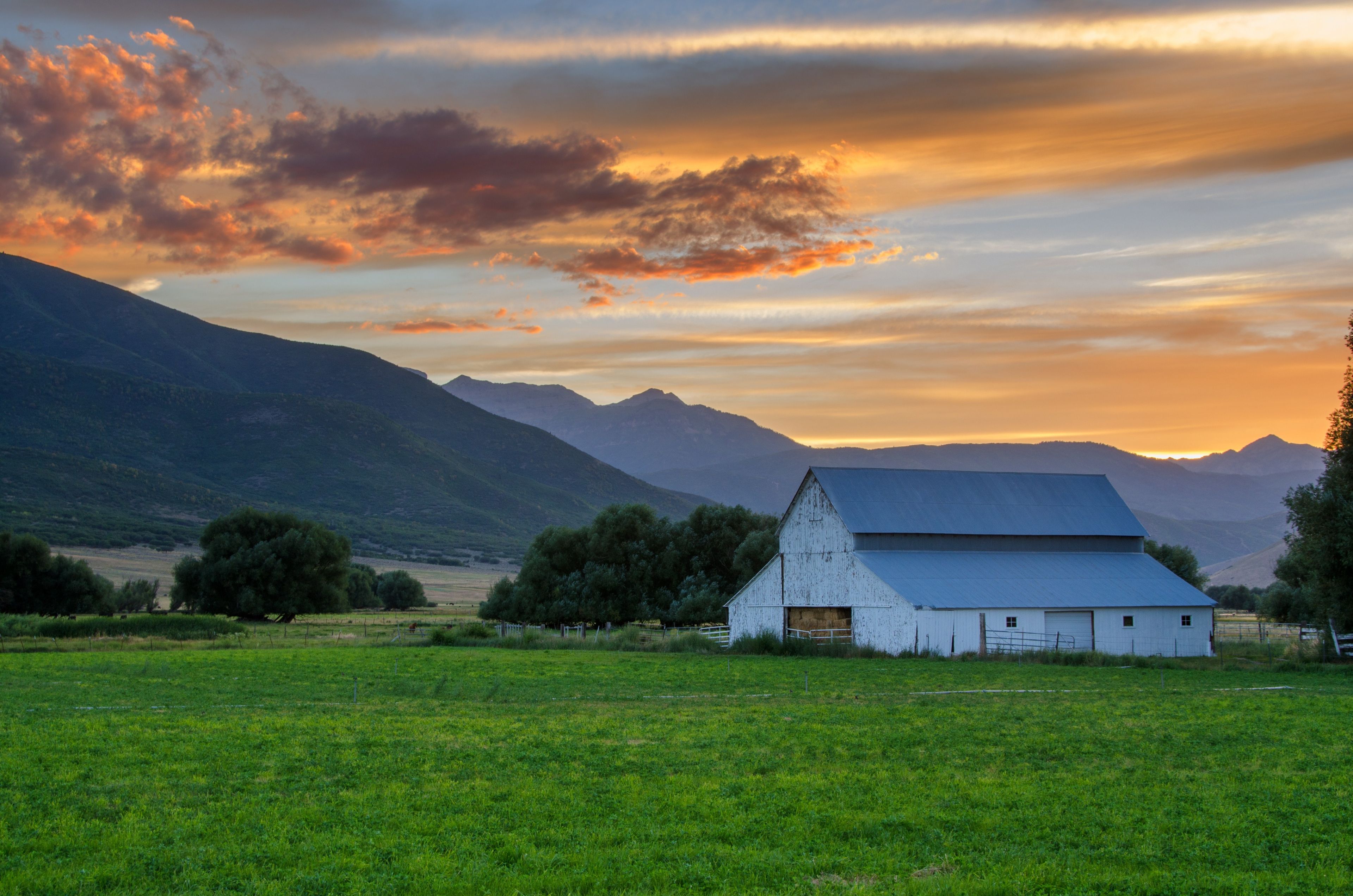 A sunset over farmland and a barn.