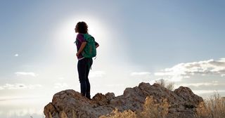 young woman standing on a rock and looking up