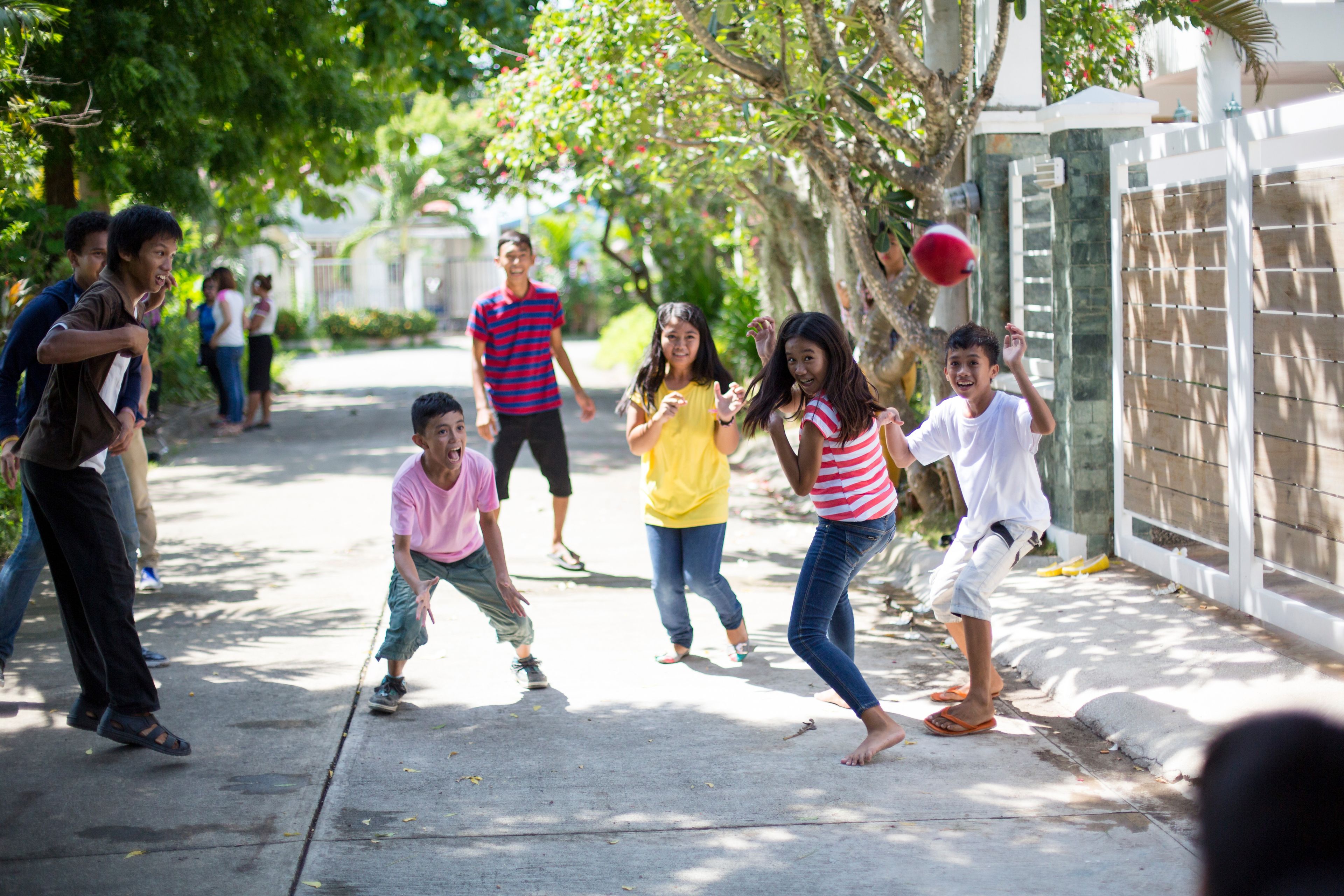 Young men and young women standing in a group and playing with a ball outside in the Philippines.  