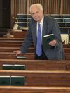 Elderly man putting away hymnbooks.