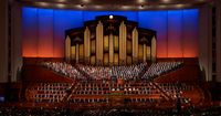 A crowd sits and watches the session inside the conference center. This is a wide shot taking in the audience and the choir. This is for the October 2018 General Conference.