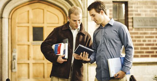 young man showing the Book of Mormon to another young man