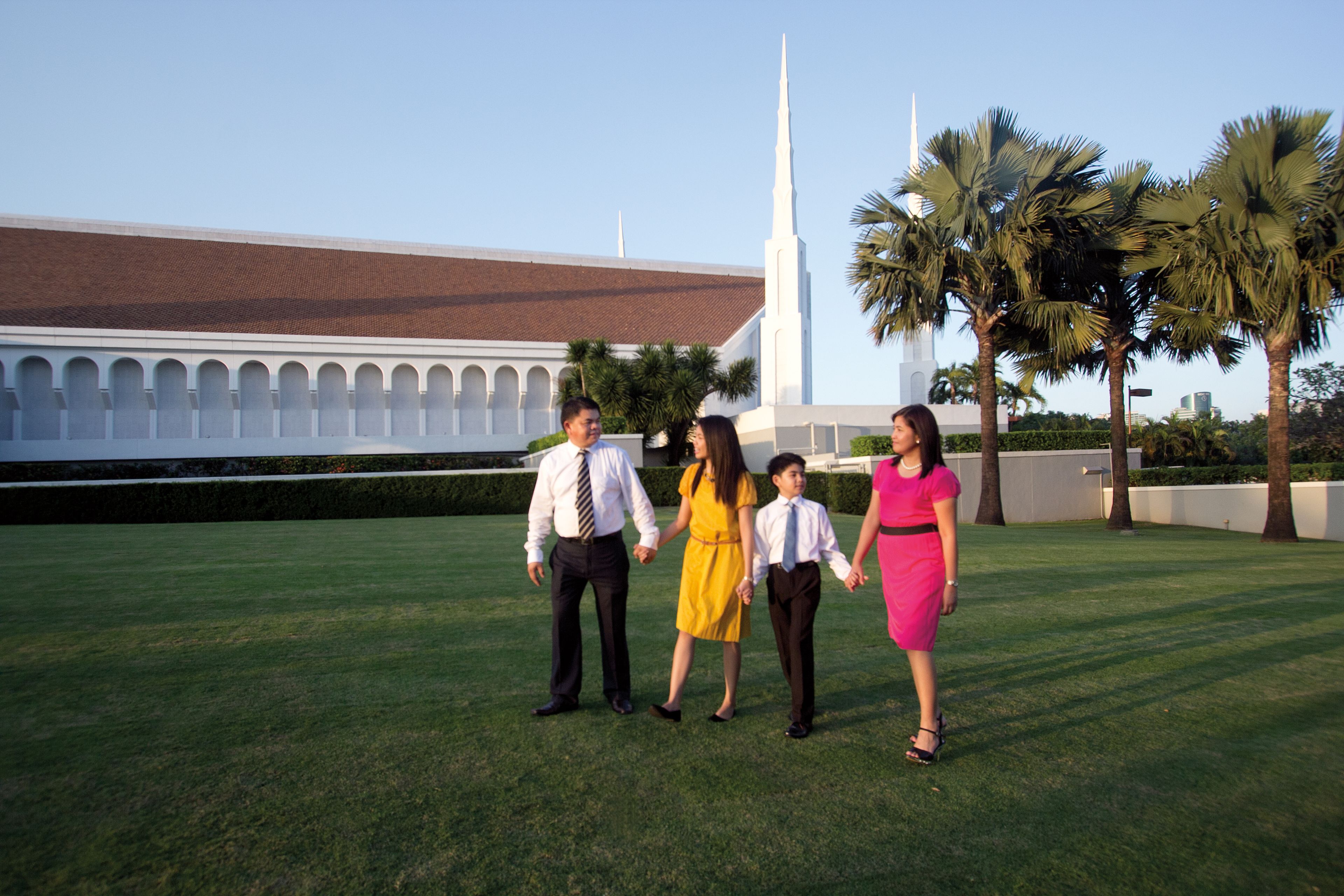 A family holding hands as they walk outside the Manila Philippines Temple.
