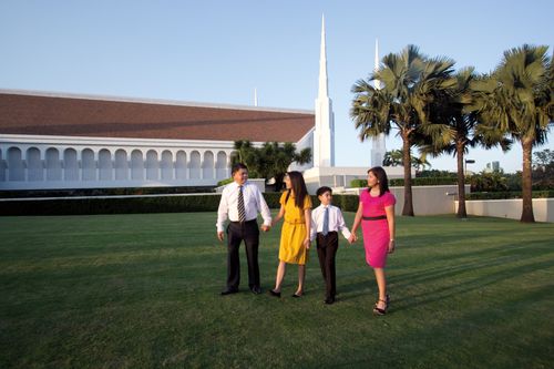A father, daughter, son, and mother walking in a row and holding hands outside the Manila Philippines Temple.
