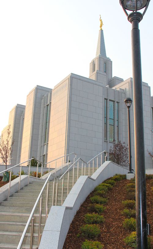 Stairs leading up to the Calgary Alberta Temple, lined with lampposts and bushes growing in flower beds.