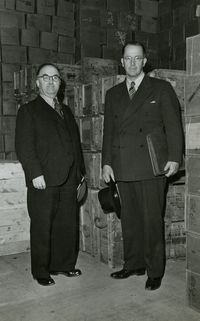Ezra Taft Benson in Geneva, Switzerland. Caption: "Checking welfare supplies with Pres. Max Zimmer in Geneva Warehouse"  Collection Summary: Black-and-white views taken during Benson's February-December 1946 mission to postwar Europe to meet with Latter-day Saints, direct distribution of welfare supplies, and arrange for resumption of missionary work.