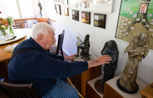 man in wheelchair looking at pieces of sculpture