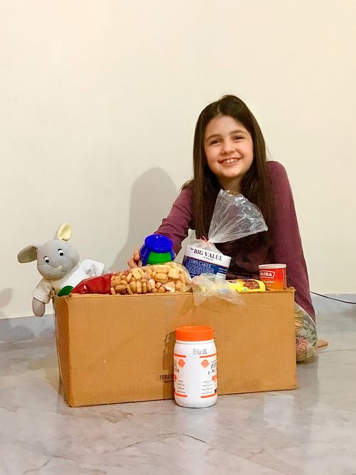 Carmen Ahmad smiles with a box full of supplies.