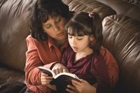 Hispanic mother and young daughter reading the Book of Mormon.