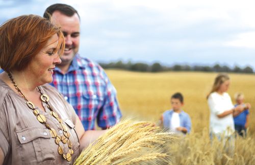 A family interacts in a wheat field on a cloudy day.